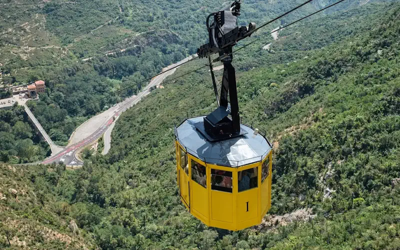 Cable car descending Montserrat mountain with panoramic forest and valley views near Barcelona